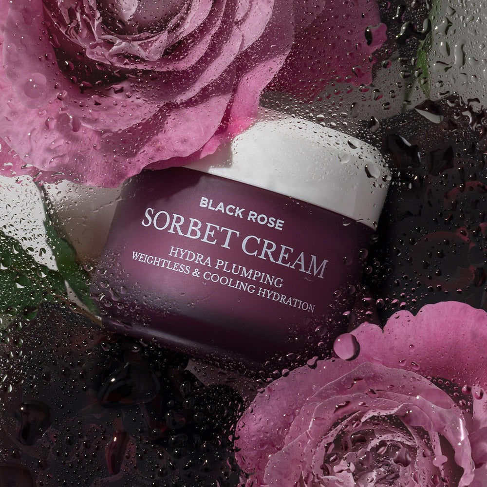 HEIMISH Black Rose Hydra Plumping Shavet Cream 50ml amidst pink roses with water droplets, highlighting hydrating properties.
