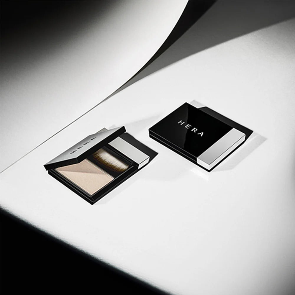 HERA Airy Powder Primer 8.5g in sleek black compact with brush, ideal for a flawless makeup base.
