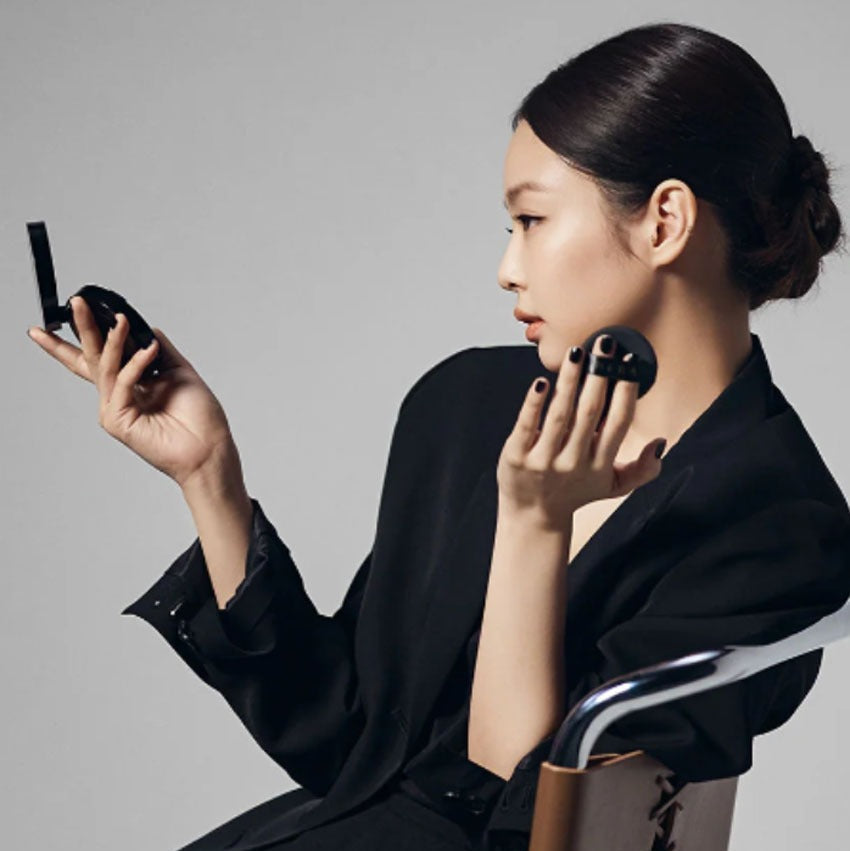 Woman applying makeup using HERA Black Cushion Foundation SPF34 PA++ 15g, showcasing its ease of use.