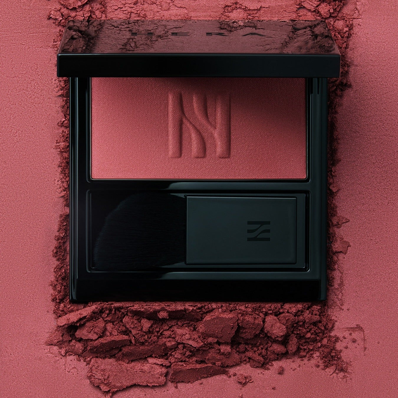 HERA Hera Blush 5.5g displayed in luxurious black casing surrounded by powdered blush texture, highlighting its rich color and premium design.