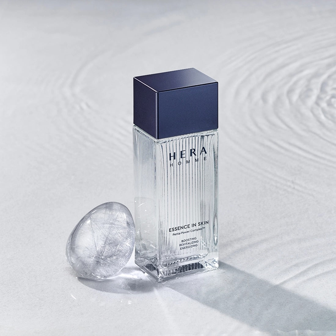 HERA Homme Essence In Skin 125ml bottle with elegant design on a textured surface.