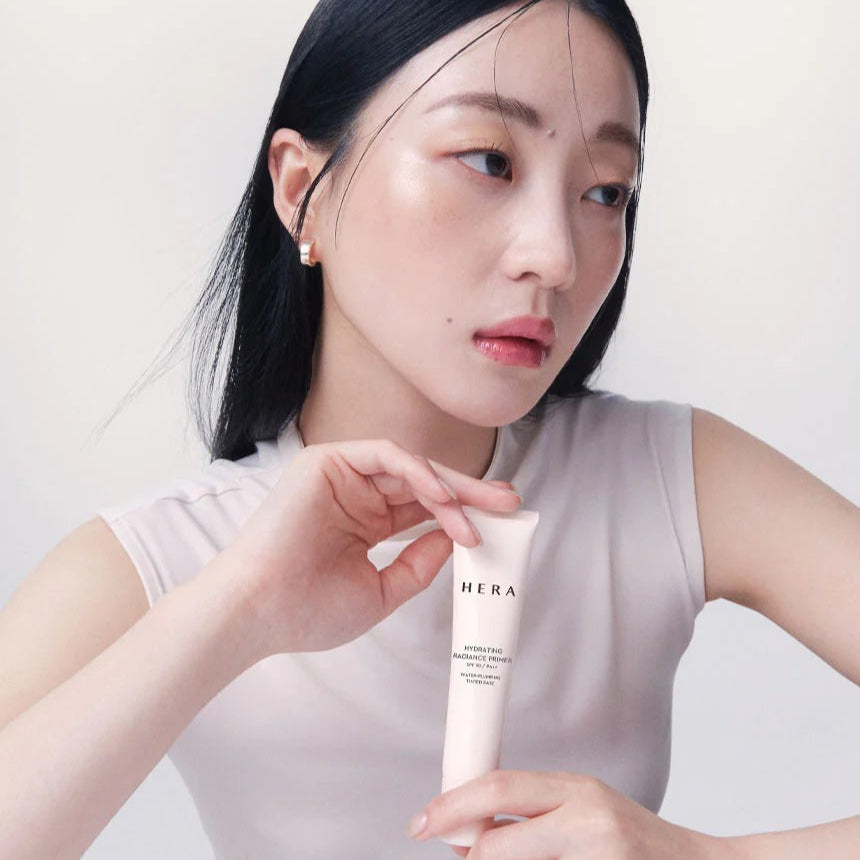 Woman holding HERA Hydrating Radiant Primer SPF30 PA++ 35ml, showcasing its hydrating and radiant properties.