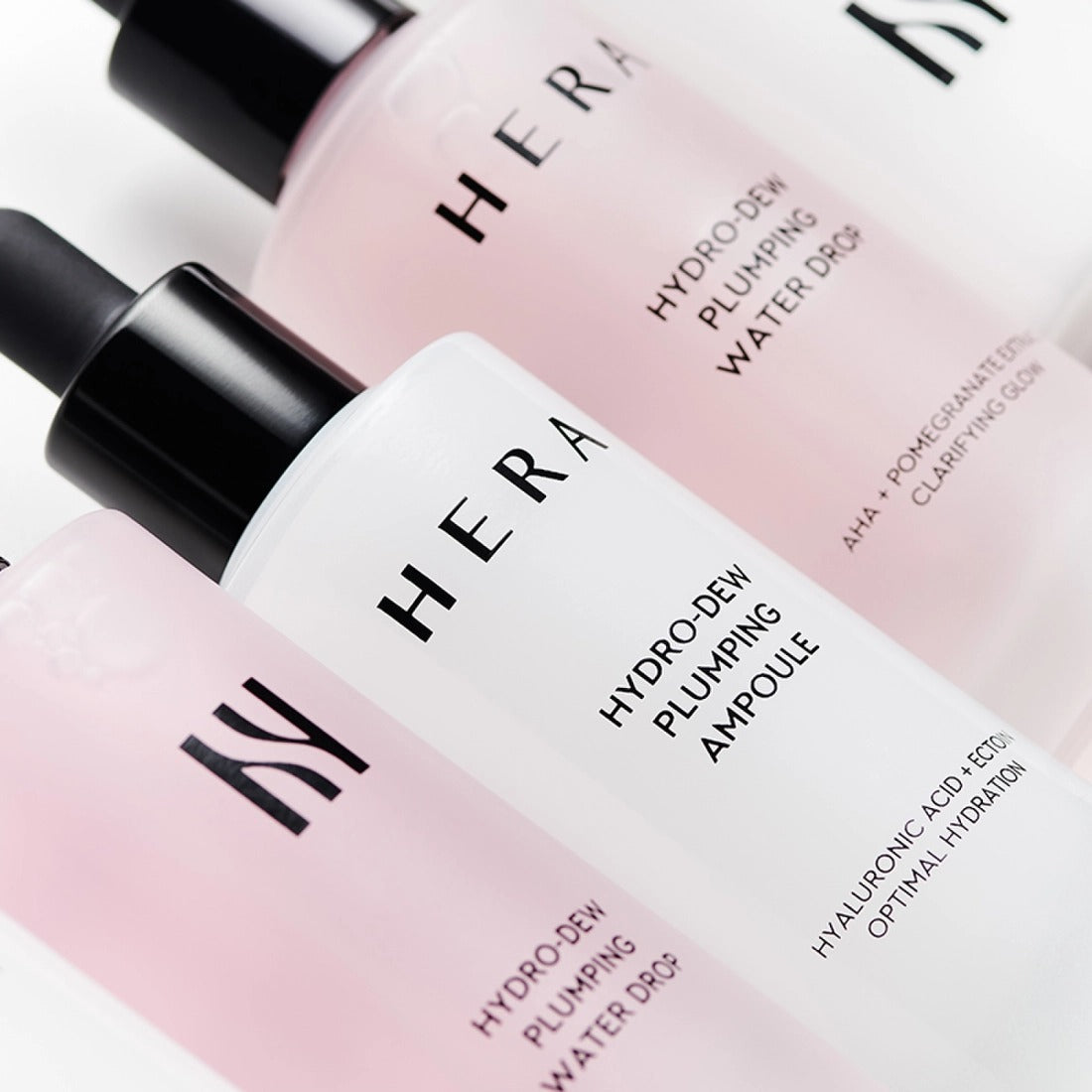 HERA Hydro-Dew Plumping Ampoule 50ml in sleek glass bottle with black dropper, surrounded by other HERA skincare products.