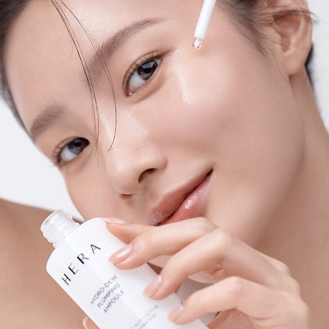 Woman applying HERA Hydro-Dew Plumping Ampoule 50ml for radiant skin