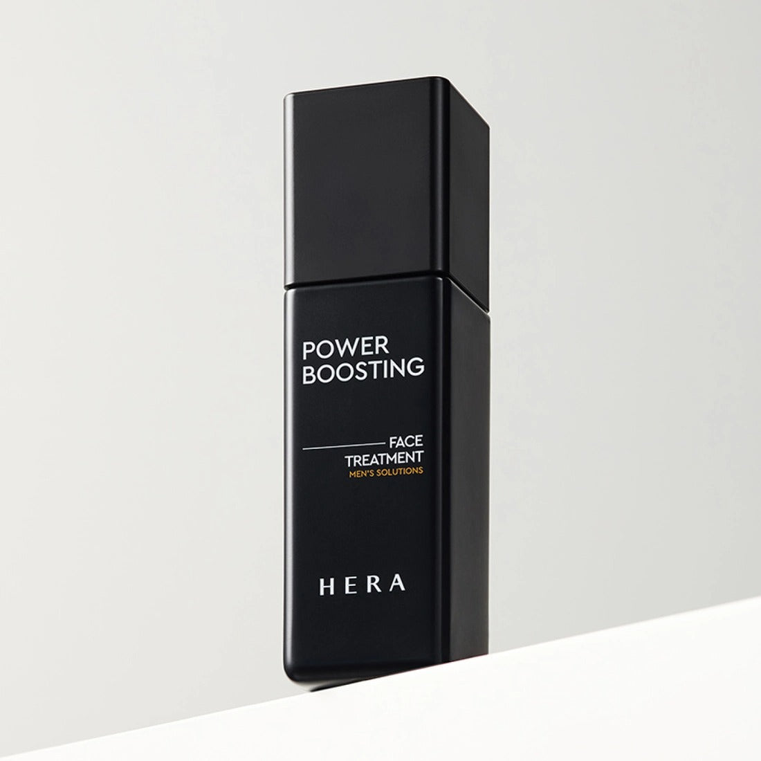 HERA Powder Boosting Face Treatment 110ml sleek black bottle design on a minimalist background.