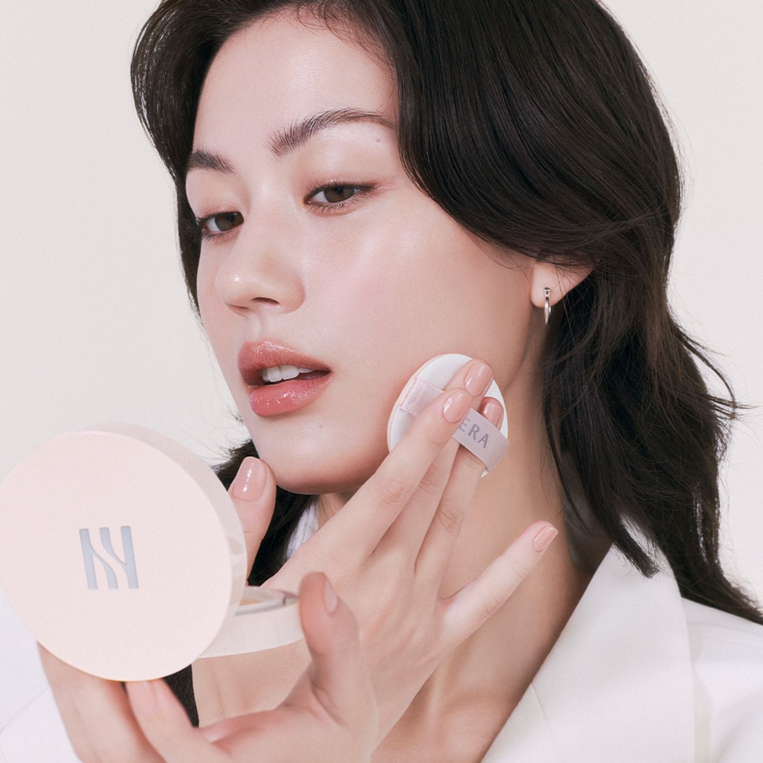 Woman applying HERA Reflection Skin Glow Cushion Foundation 15g for a radiant look.
