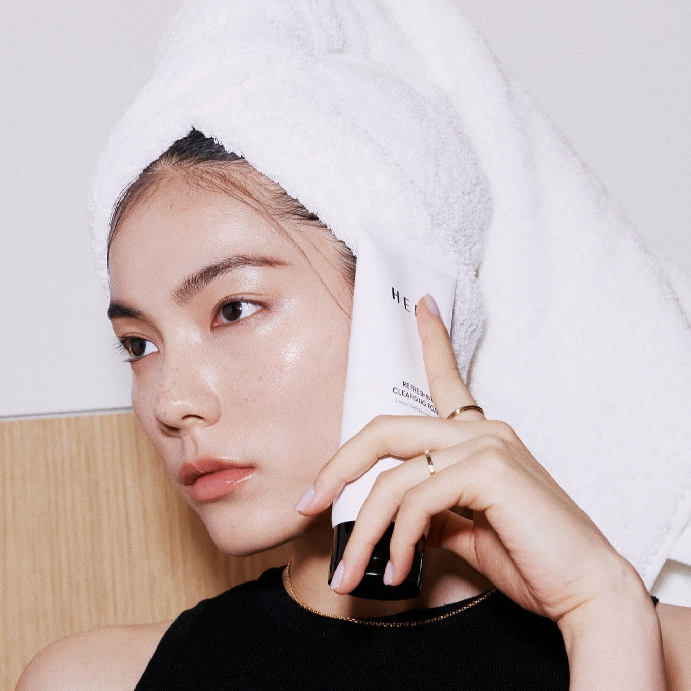 Woman holding HERA Refreshing Cleansing Foam 160g, showcasing skincare routine