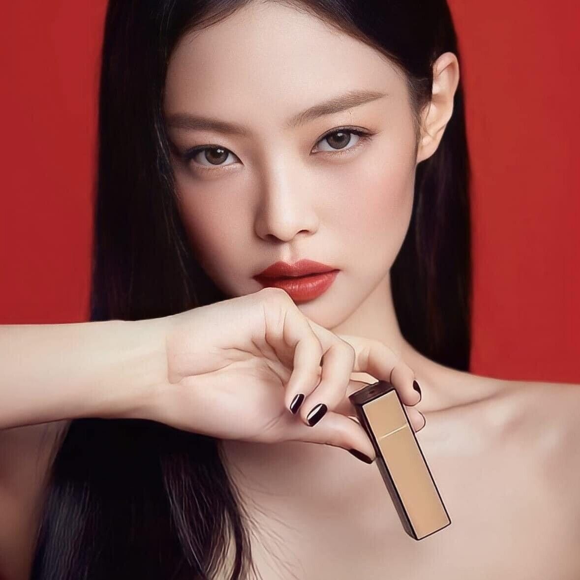 Woman holding HERA Rouge Clasyy 3.5g lipstick with a bold red background