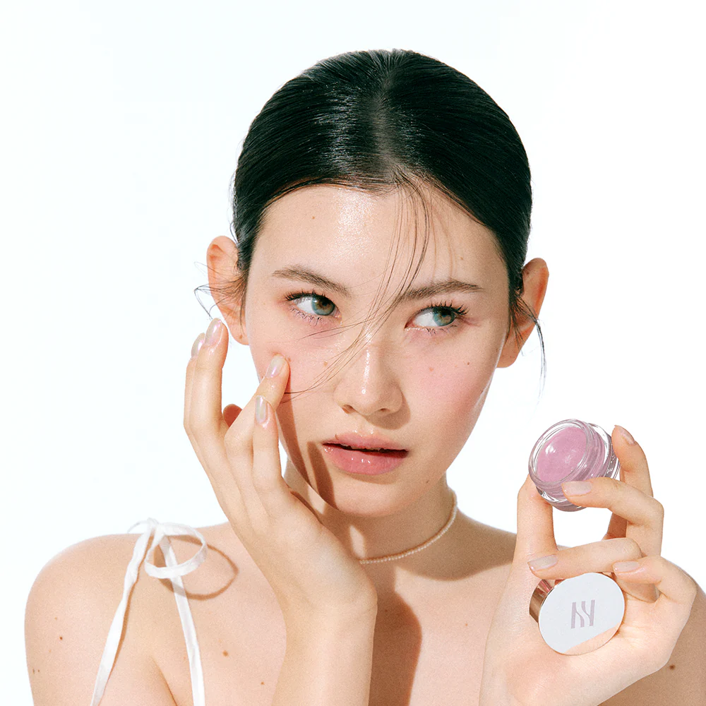 Model applying HERA Sensual Lip & Cheek 7g softly on cheeks for a natural blush effect.