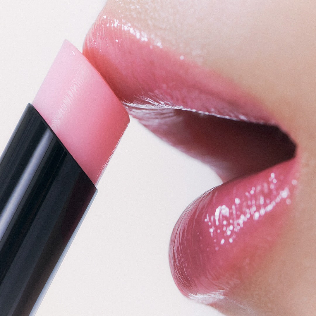 Close-up of lips applying HERA Sensual Nude Balm 3.5g for a glossy and nourished finish.