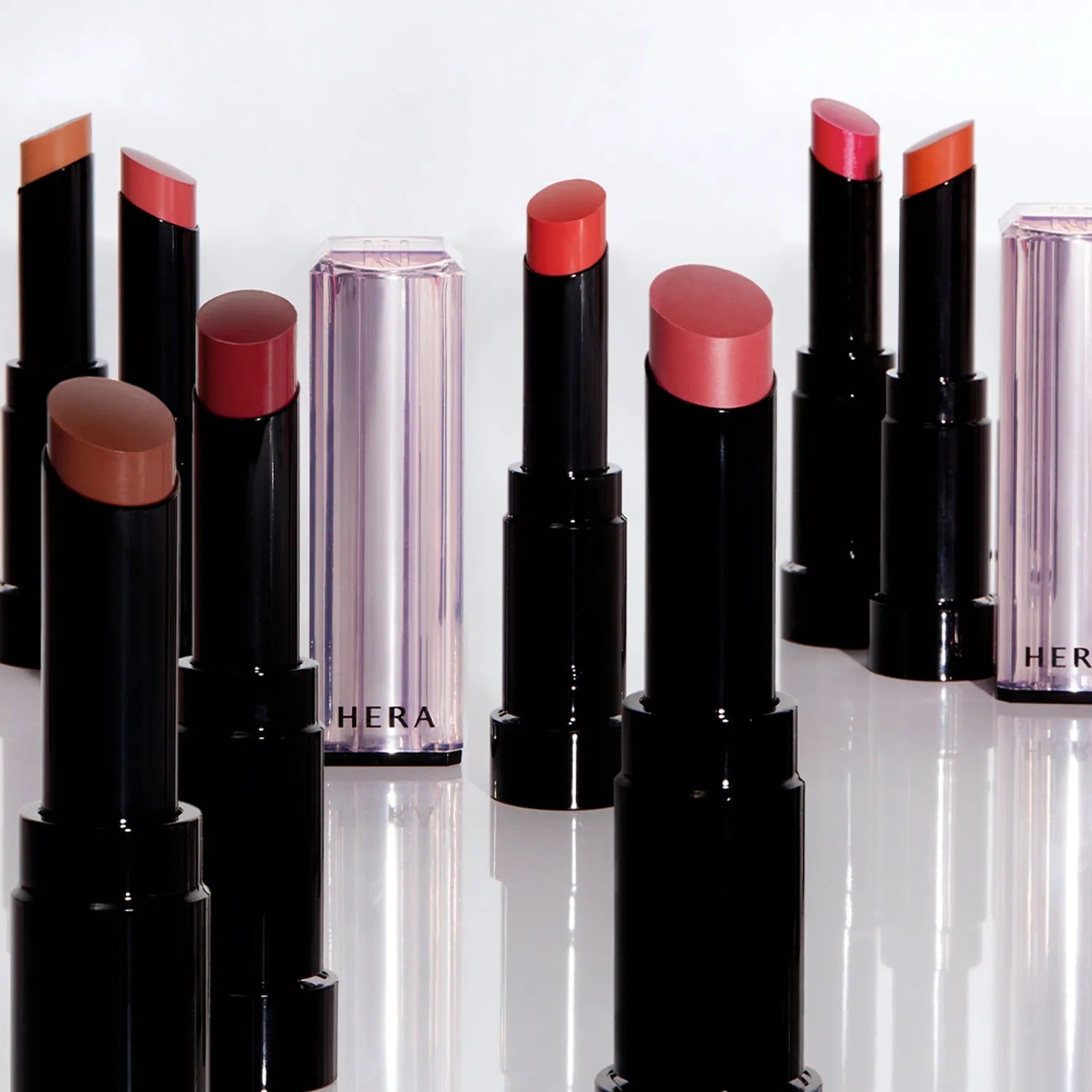 Assorted shades of HERA Sensual Tinted Shine Stick 3.5g displayed creatively on a white background.