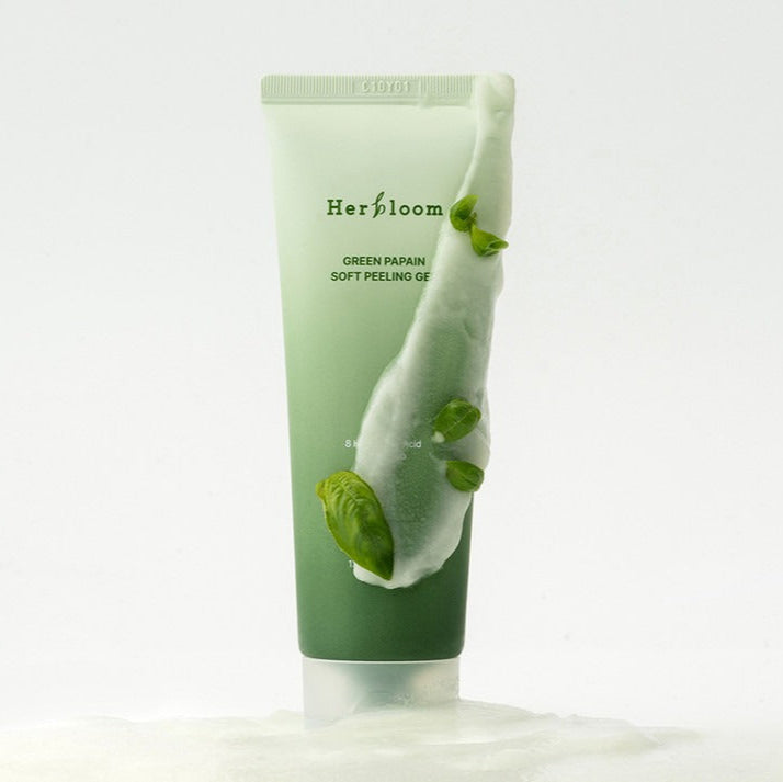HERBLOOM Green Papain Soft Peeling Gel 120g in a sleek green tube with fresh green leaves on a white background.