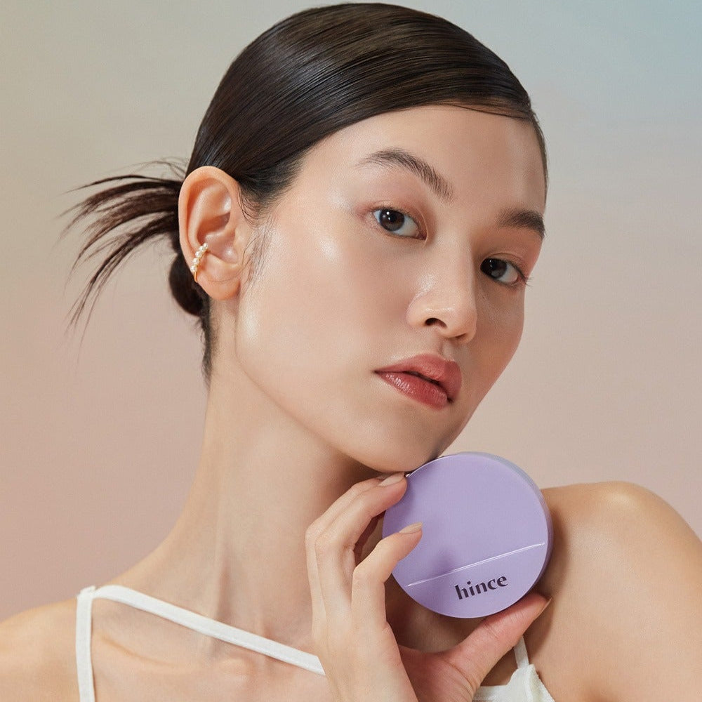 Model holding HINCE Second Skin Glow Cushion 12g, showcasing its sleek design and vibrant packaging.