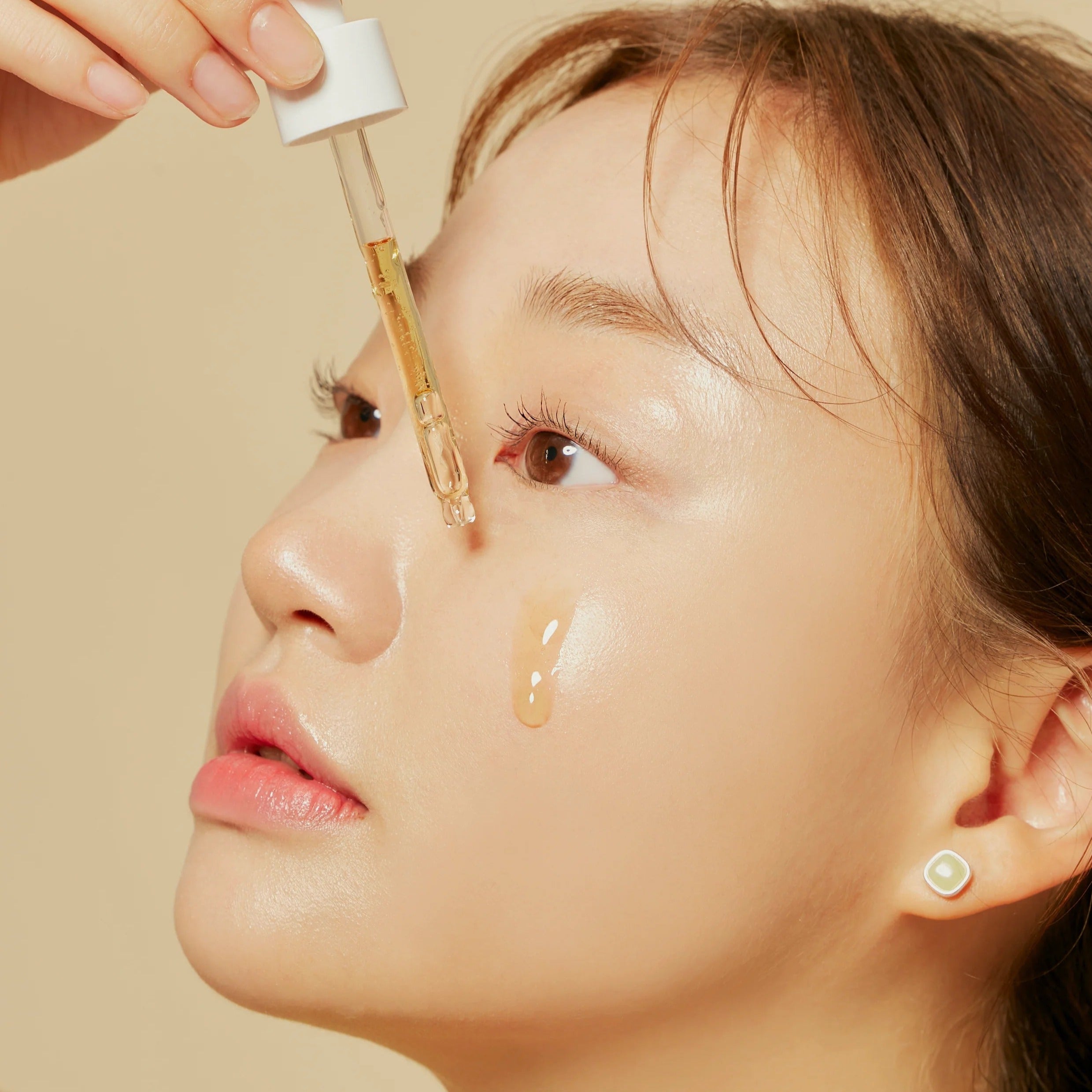 Woman applying HYGGEE Own Vegan Calming Serum 50ml on skin for soothing and hydration.