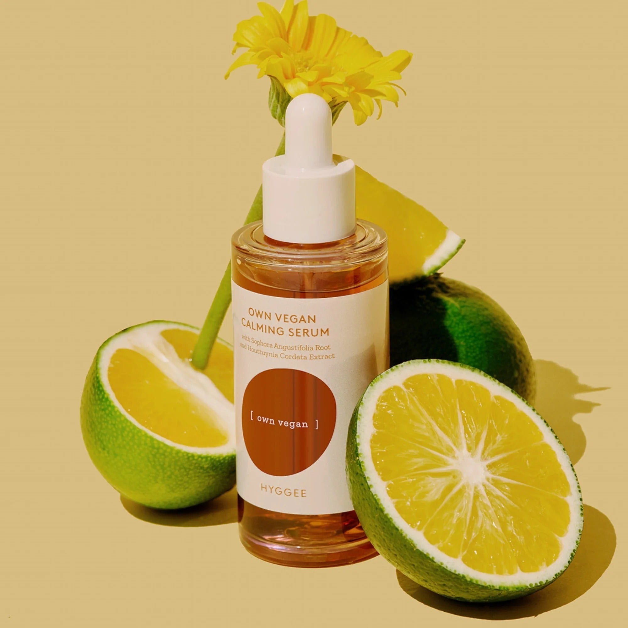 HYGGEE Own Vegan Calming Serum 50ml with fresh lemons and a daisy on a yellow background.