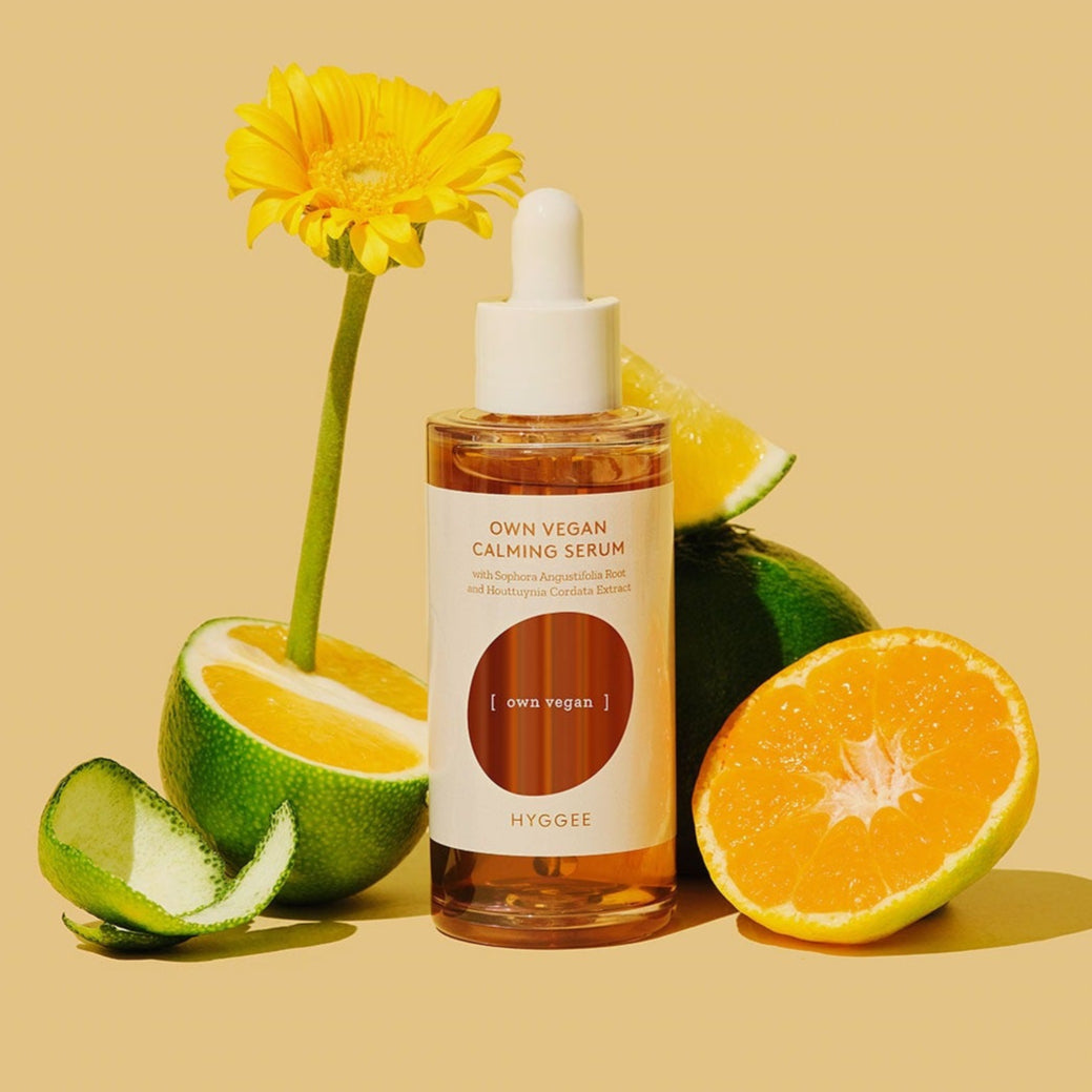 HYGGEE Own Vegan Calming Serum 50ml bottle surrounded by fresh citrus and a yellow flower, showcasing the natural ingredients.