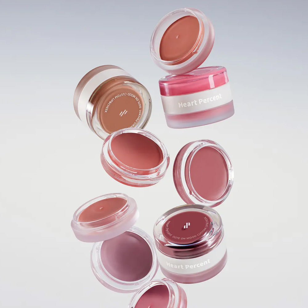 HEART PERCENT Dot On Mood Custom Lip & Cheek collection showcasing various shades in open containers on a soft gradient background.