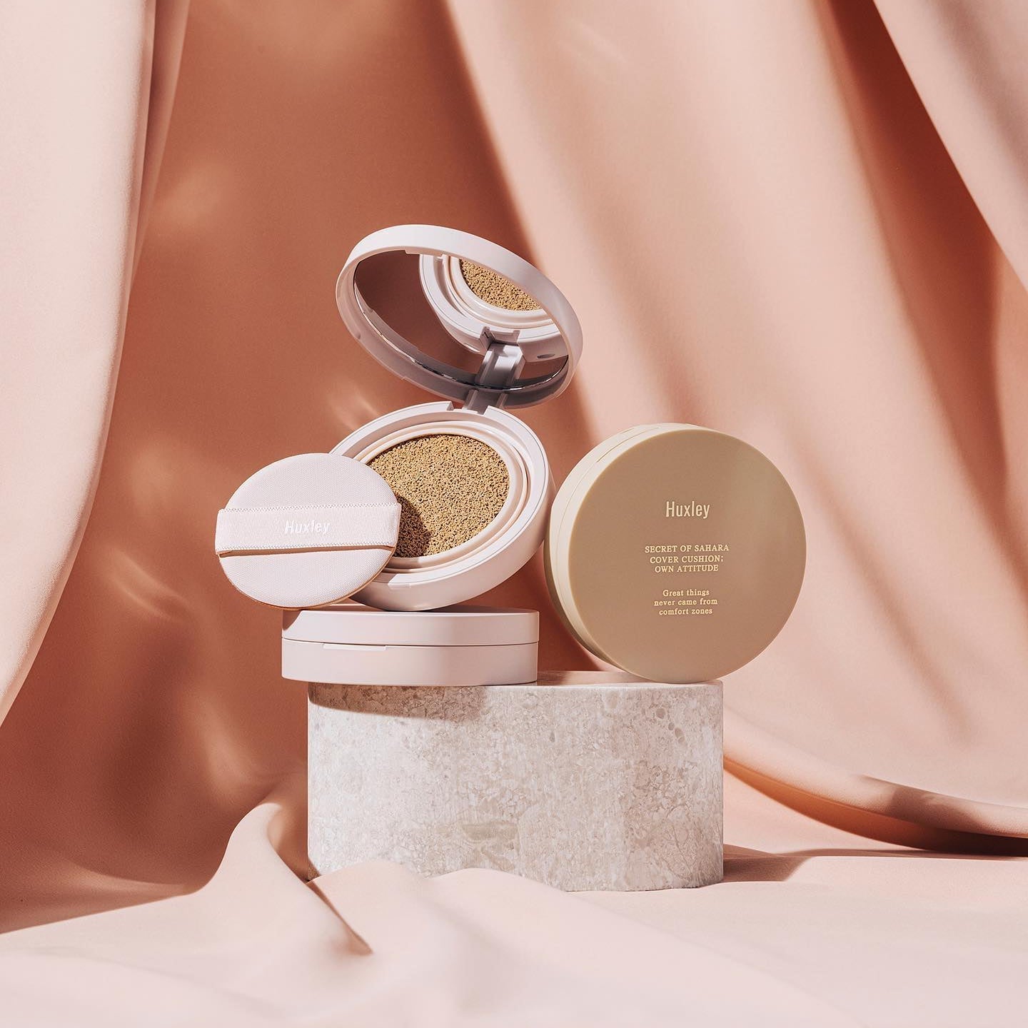 HUXLEY Cover Cushion Own Attitude displayed against a soft fabric background, showcasing its sleek packaging and premium design.