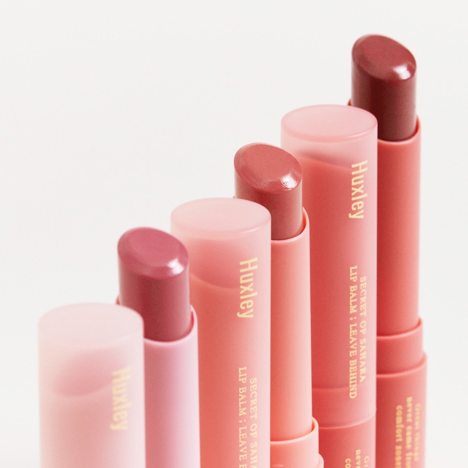HUXLEY Lip Balm Leave Behide in multiple shades, showcasing luxury lip care with vibrant colors.