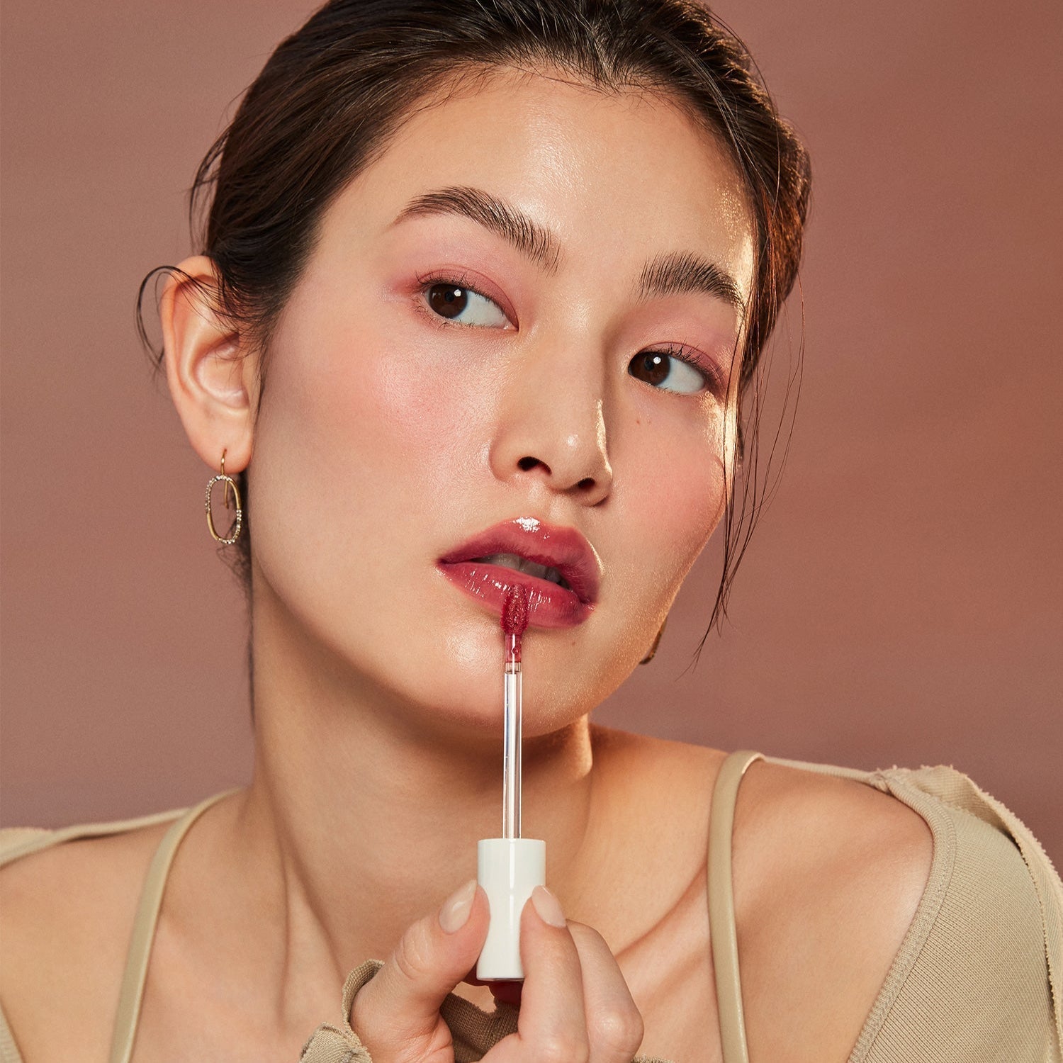 Woman applying HINCE Mood Enhancer Water Liquid Glow on her lips for a radiant finish.