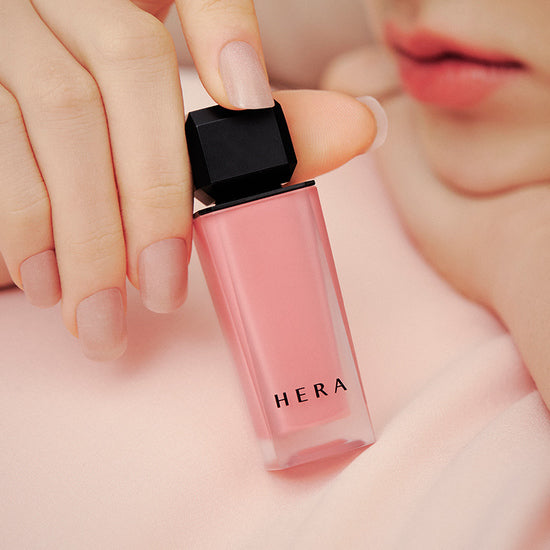 HERA Sensual Powder Matte Liquid in soft nude shade, elegant bottle held by hand, perfect matte finish for modern beauty enthusiasts.